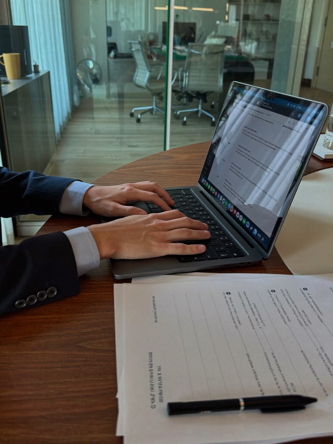 Hands typing a job description on a laptop in a meeting room