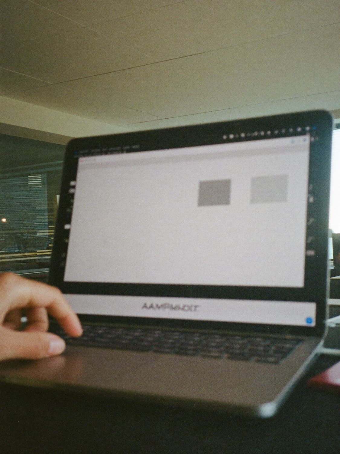 A laptop on a desk seen from the side, the page on screen out of focus